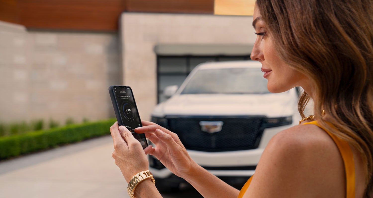 lady checking her mobile with a Cadillac vehicle background | Earnhardt Chandler Cadillac in Chandler AZ